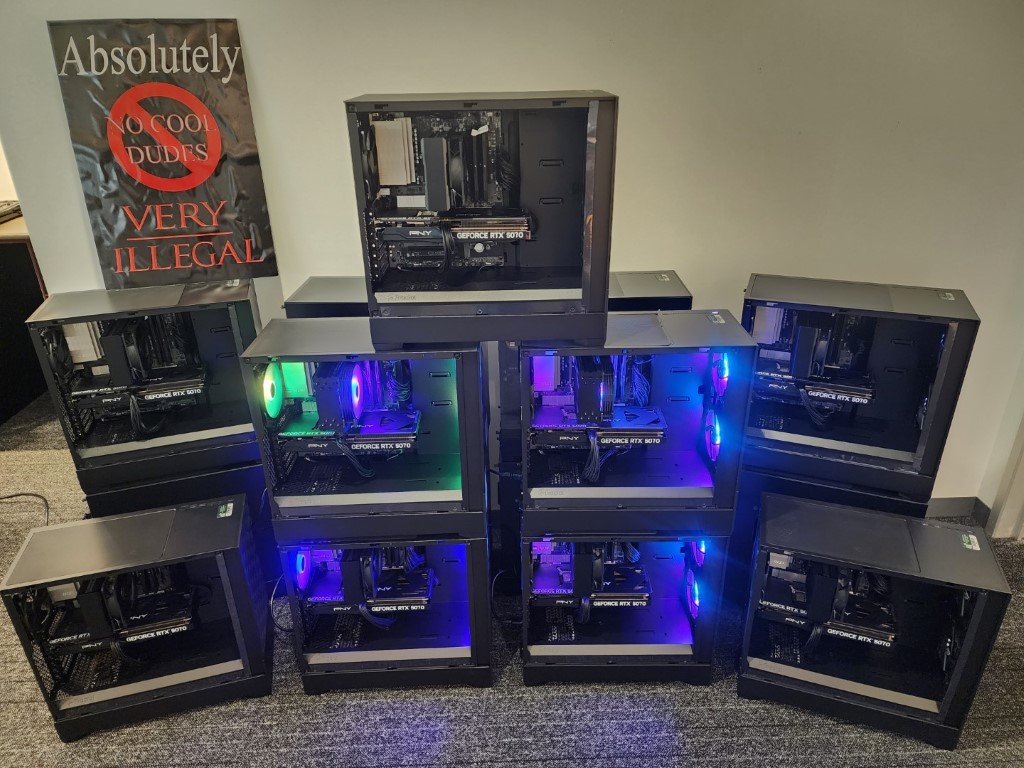 Pyramid stack of nine black Fractal towers with RTX 5070 cards and green and blue RGB, next to a NO COOL DUDES poster