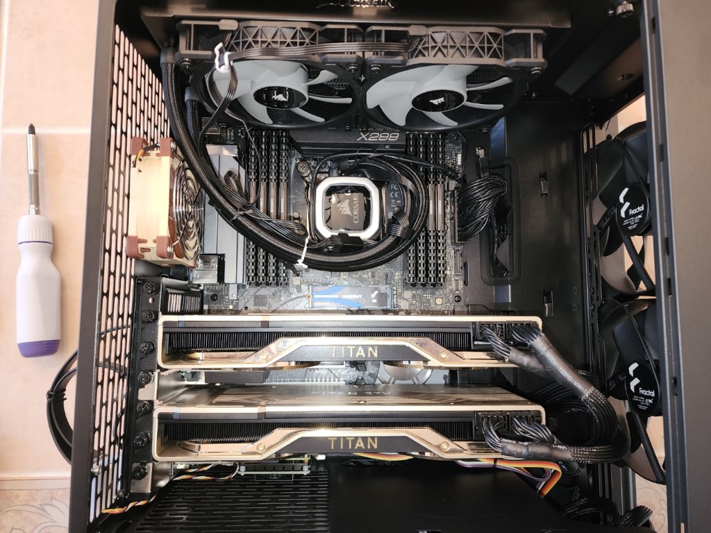 High-end build with two gold and black NVIDIA Titans, a Corsair liquid cooler, and an X299 motherboard