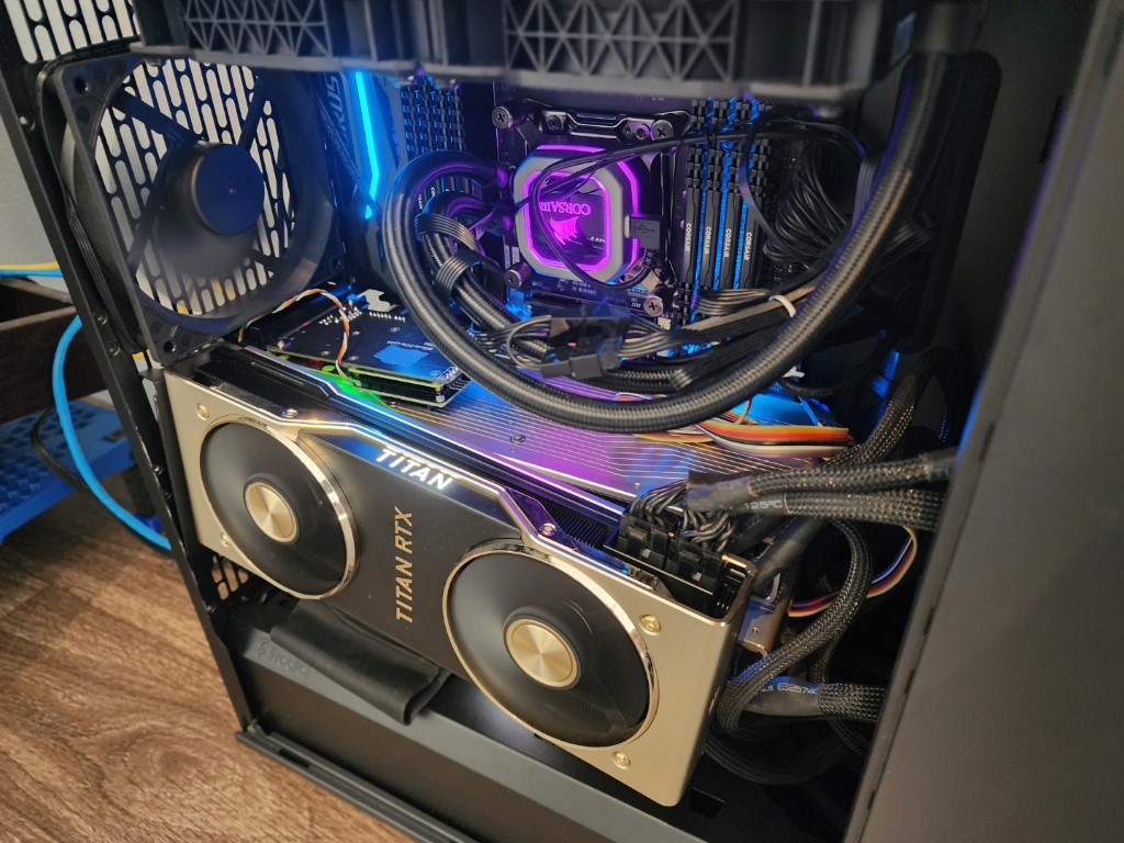 Gold and black Titan RTX graphics card with a purple-glowing Corsair cooler and four RAM sticks on a blue-lit board