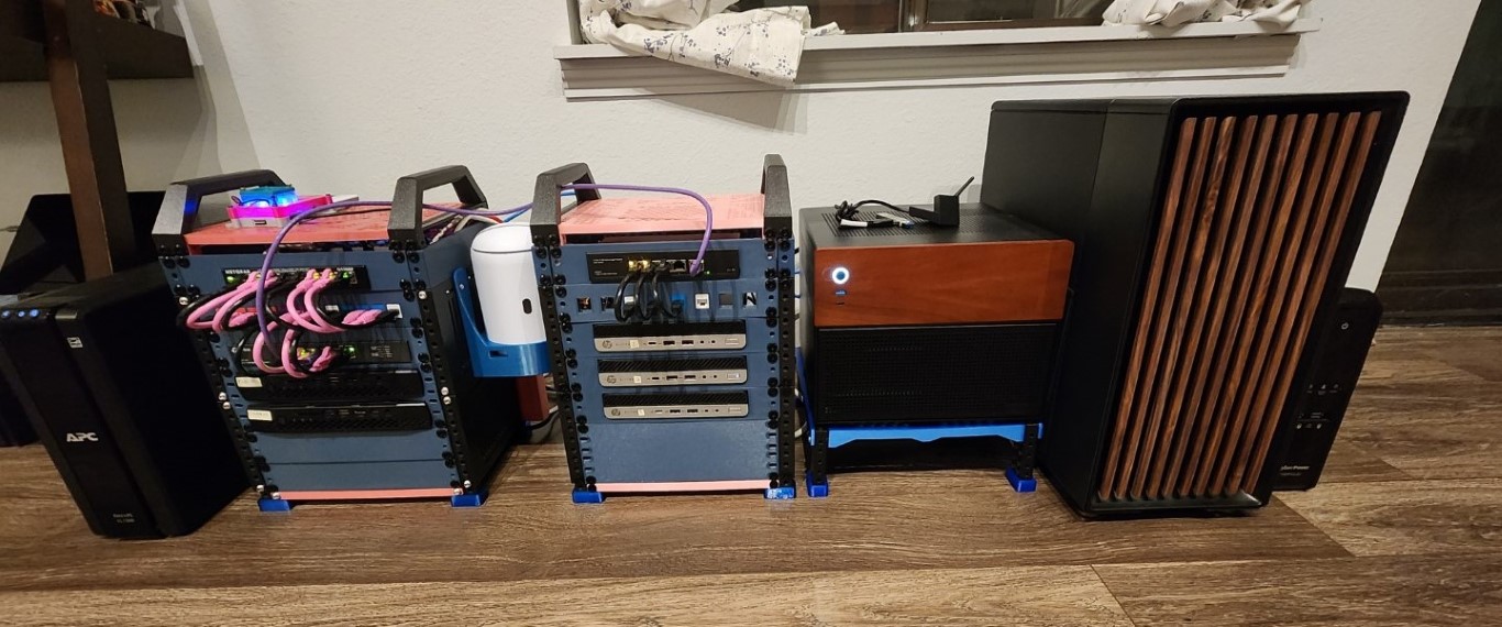 Home data center: a row of server racks, network gear, and a black tower with a wood-slat front along a white wall